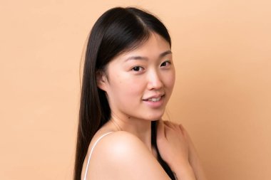 Genç Çinli kadın bej arka planda izole edilmiş. Portre