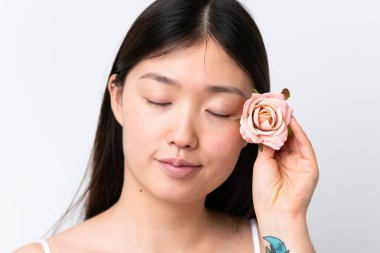 Beyaz arka planda çiçek tutan genç bir Çinli kadın. Portreyi kapat