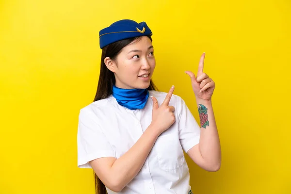 Airplane Chinese woman stewardess isolated on yellow background pointing with the index finger a great idea