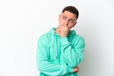 Beyaz arka planda izole edilmiş genç Brezilyalı adamın şüpheleri ve şaşkın bir yüz ifadesi var.