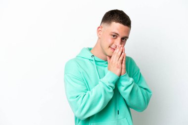 Beyaz arka planda izole edilmiş genç Brezilyalı adam avuç içlerini bir arada tutuyor. İnsan bir şey ister.