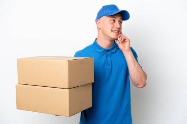 Young delivery Brazilian man isolated ops white background thinking an idea while looking up