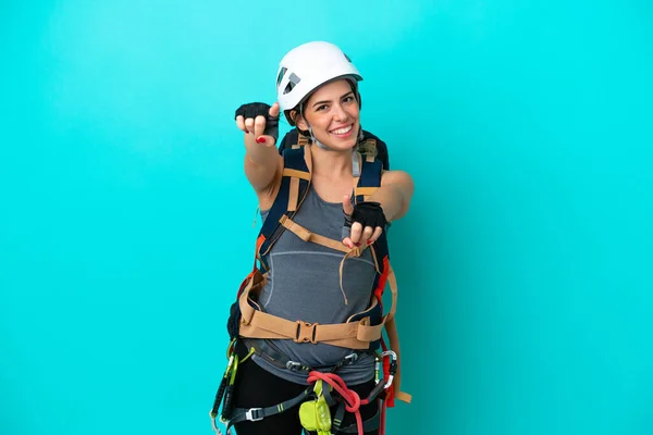 Young Italian rock-climber woman isolated on blue background points finger at you while smiling