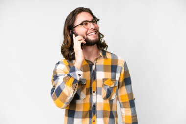 Soyutlanmış beyaz arka planda genç yakışıklı bir adam cep telefonuyla sohbet ediyor.