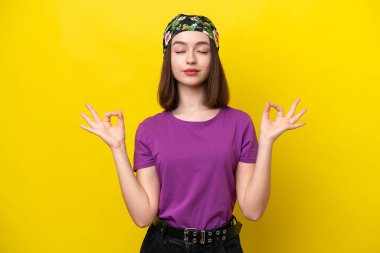 Genç Ukraynalı kadın Zen pozunda sarı arka planda izole edilmiş.