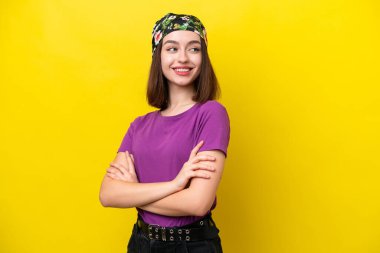 Young Ukrainian woman isolated on yellow background with arms crossed and happy