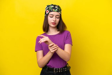 Young Ukrainian woman isolated on yellow background suffering from pain in hands