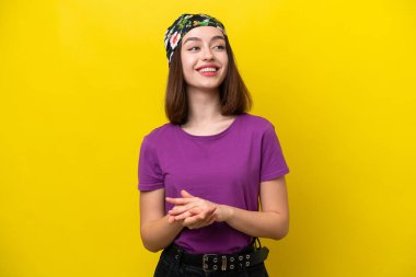 Young Ukrainian woman isolated on yellow background applauding
