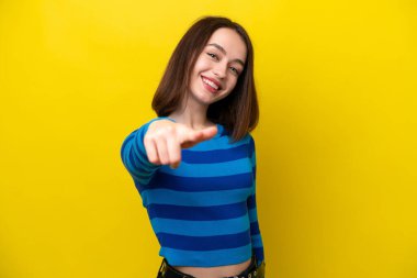 Young Ukrainian woman isolated on yellow background pointing front with happy expression