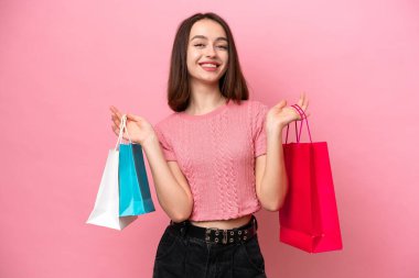 Pembe arka planda izole edilmiş genç Ukraynalı bir kadın alışveriş torbaları tutuyor ve gülümsüyor.