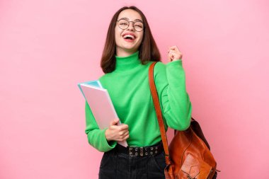 Young student Ukrainian woman isolated on pink background celebrating a victory
