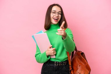 Young student Ukrainian woman isolated on pink background surprised and pointing front