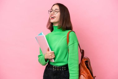 Young student Ukrainian woman isolated on pink background laughing in lateral position