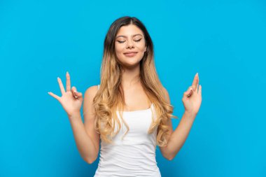 Young Russian girl isolated on blue background in zen pose