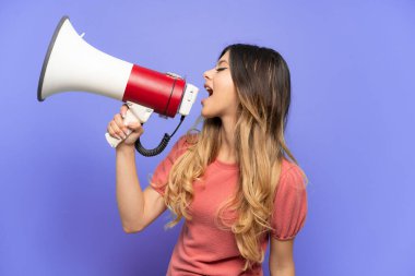 Mavi arka planda izole edilmiş genç bir Rus kız megafonla bir şey duyurmak için bağırıyor.