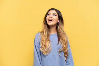 Sarı arka planda yalnız yaşayan genç Rus kız gülüyor.