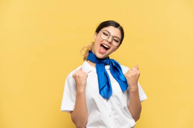 Airplane stewardess isolated on yellow background celebrating a victory in winner position