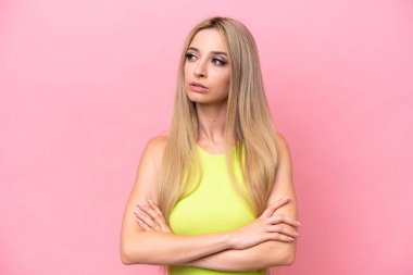 Pretty blonde woman isolated on pink background looking to the side