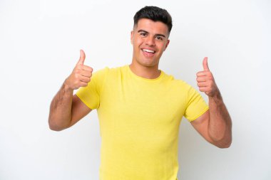 Beyaz arka planda izole edilmiş beyaz, beyaz, yakışıklı genç bir adam baş parmak işareti yapıyor.