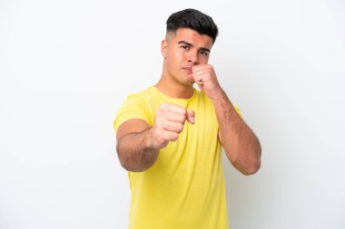 Beyaz arka planda savaşan beyaz tenli yakışıklı genç bir adam.