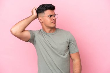 Young caucasian handsome man isolated on pink background having doubts while scratching head