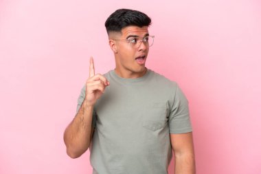 Pembe arka planda soyutlanmış beyaz, yakışıklı bir adam çözümü bulmak için parmağını kaldırıyor.