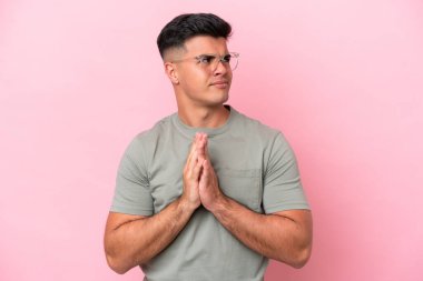 Beyaz tenli yakışıklı bir adam pembe arka planda izole edilmiş bir şeyler çeviriyor.