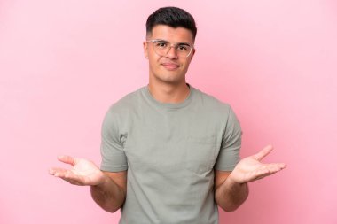 Pembe arka planda izole edilmiş beyaz, yakışıklı genç bir adam. Şüpheleri var.