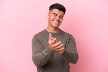 Beyaz tenli yakışıklı adam pembe arka planda izole edilmiş bir konferansta sunumdan sonra alkışlıyor.