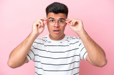 Young caucasian handsome man isolated on pink background With glasses and frustrated expression