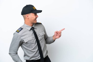 Beyaz arka planda izole edilmiş beyaz tenli genç bir güvenlik elemanı parmak göstererek bir ürün sunuyor.
