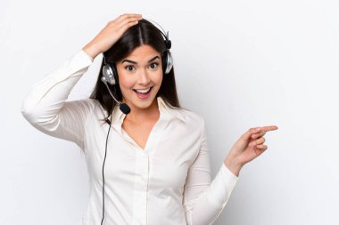 Beyaz arka planda izole edilmiş kulaklıkla çalışan beyaz pazarlamacı kadın şaşırdı ve parmağını yana çevirdi.