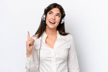 Beyaz arka planda izole edilmiş bir kulaklıkla çalışan beyaz pazarlamacı kadın çözümü fark ederken parmağını kaldırmayı amaçlıyor.