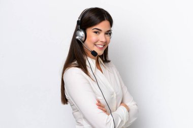 Telemarketer caucasian woman working with a headset isolated on white background with arms crossed and looking forward