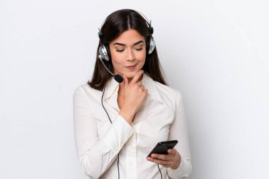 Telemarketer caucasian woman working with a headset isolated on white background thinking and sending a message