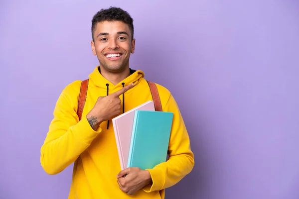 Young student Brazilian man isolated on purple background pointing to the side to present a product