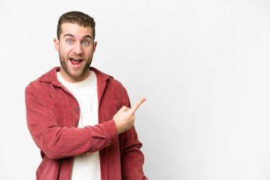 Yakışıklı sarışın, soyutlanmış beyaz bir arka plan. Şaşırmış ve işaret ediyor.