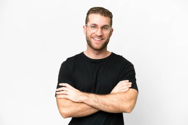 Sarışın, yakışıklı, soyutlanmış beyaz arka planda genç bir adam kollarını ön cephede kavuşturuyor.