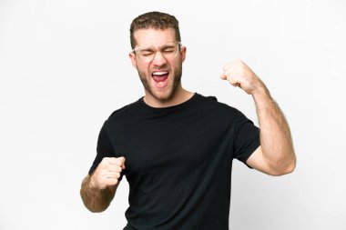 Genç yakışıklı sarışın adam izole edilmiş beyaz arka plan zaferi kutluyor.