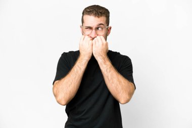 Young handsome blonde man over isolated white background nervous and scared putting hands to mouth