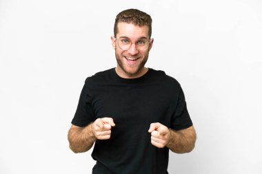 Young handsome blonde man over isolated white background surprised and pointing front