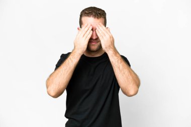Genç, sarışın, soyutlanmış, beyaz arka planda, gözleri elleriyle kaplayan adam.