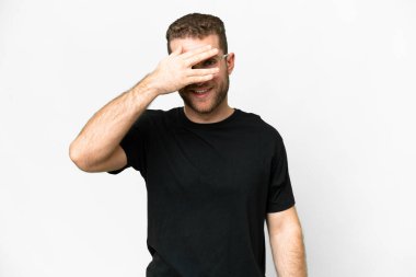 Young handsome blonde man over isolated white background covering eyes by hands and smiling