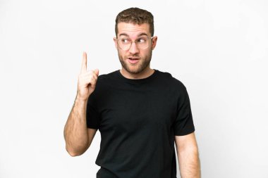 Genç, sarışın, soyutlanmış beyaz arka planda bir parmağını kaldırarak çözümü bulmaya çalışan bir adam.