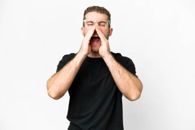 Genç, sarışın, soyutlanmış beyaz arka planda bir adam bağırıyor ve bir şey duyuruyor.