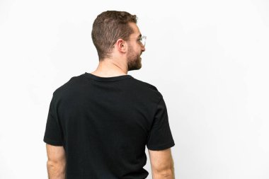 Young handsome blonde man over isolated white background in back position and looking side