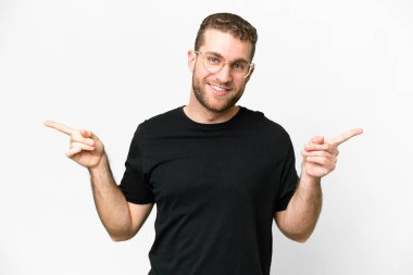 Young handsome blonde man over isolated white background pointing finger to the laterals and happy