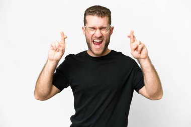 Young handsome blonde man over isolated white background with fingers crossing