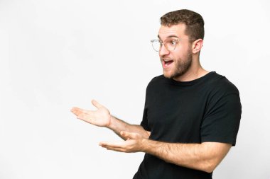 Young handsome blonde man over isolated white background with surprise expression while looking side