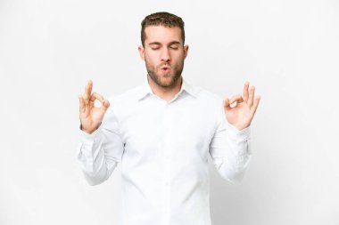 Zen pozisyonunda, soyutlanmış beyaz arka planda yakışıklı sarışın bir adam.